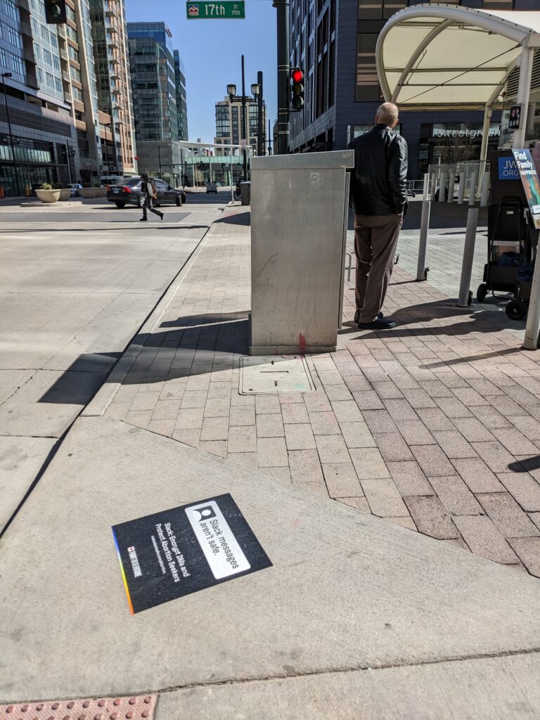 Sidewalk decal with text "Slack Messages Aren't Safe. Slack: Encrypt DMs and Protect Abortion Seekers makeslacksafe.com/abortion"